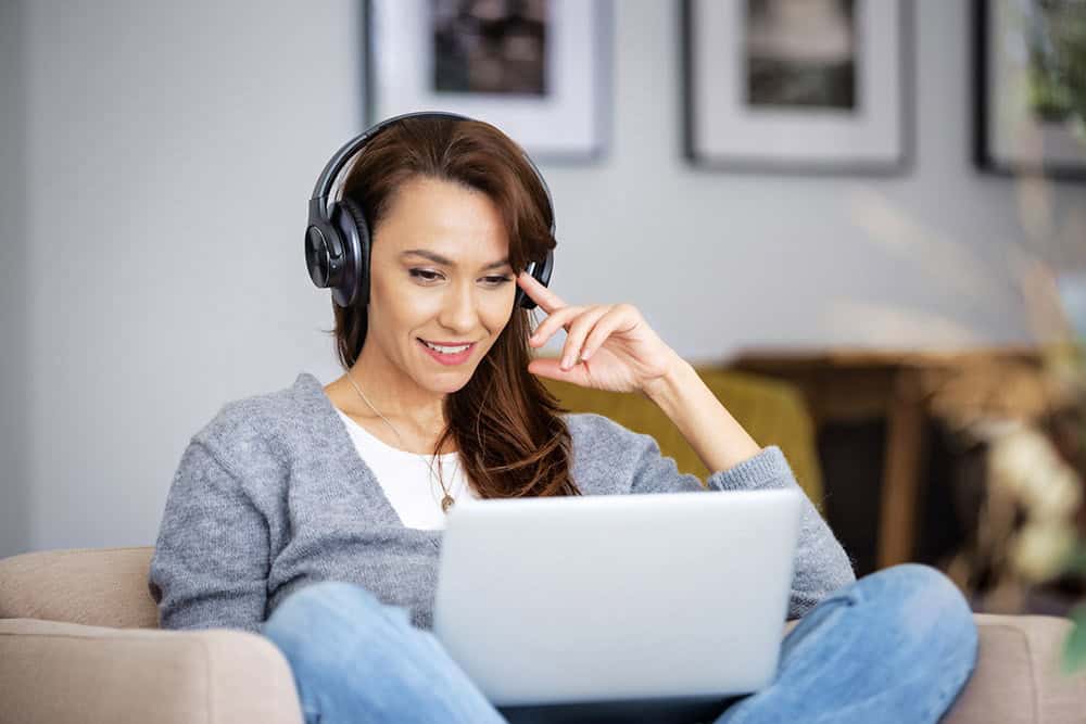 woman sitting on couch listens to real estate audio courses